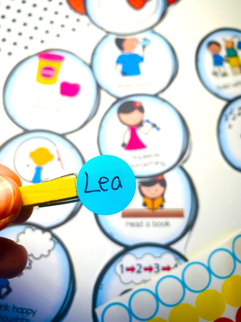 "Supplies laid out for making the Snowman Calm Down Clip Chart, including printed snowman pieces, clothespins with dot stickers, scissors, and markers.