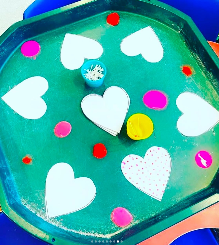 Valentine’s Day Tuff Tray filled with red and pink sensory materials and matching activities.