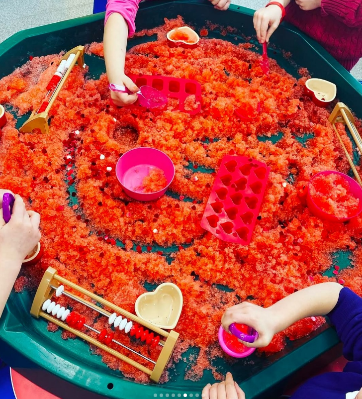 An overhead shot of a complete Valentine’s Day Tuff Tray setup, ready for toddler play.