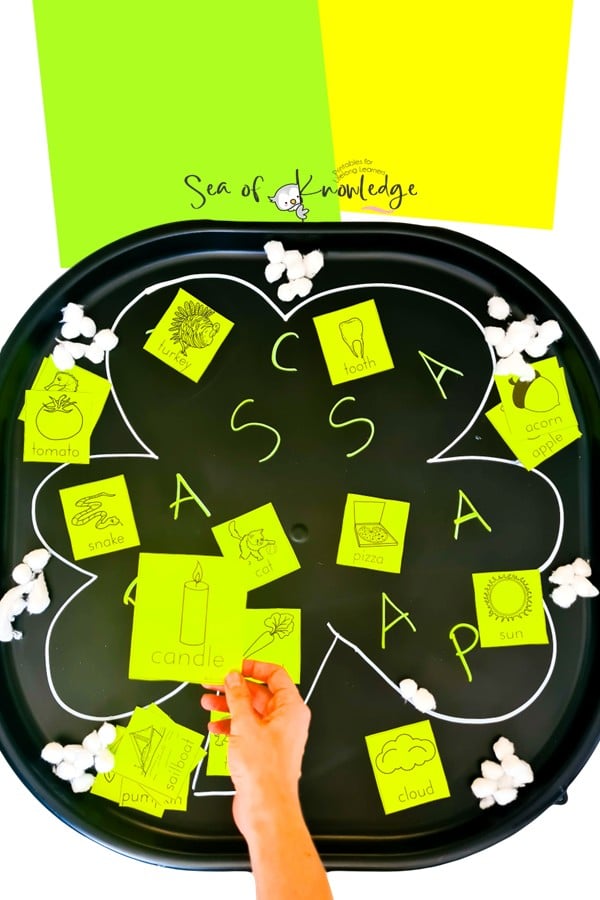 Tuff tray phonics activity featuring a large shamrock cutout with matching letter sounds.
