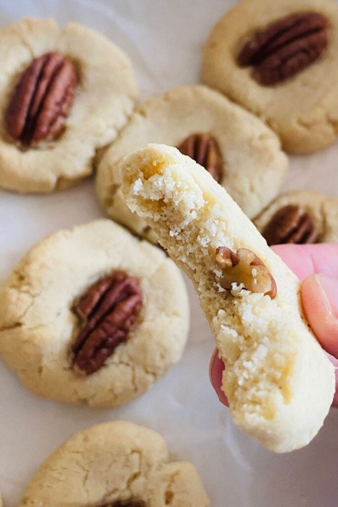 Stack of almond pecan shortbread cookies on a plate with a cup of tea in the background