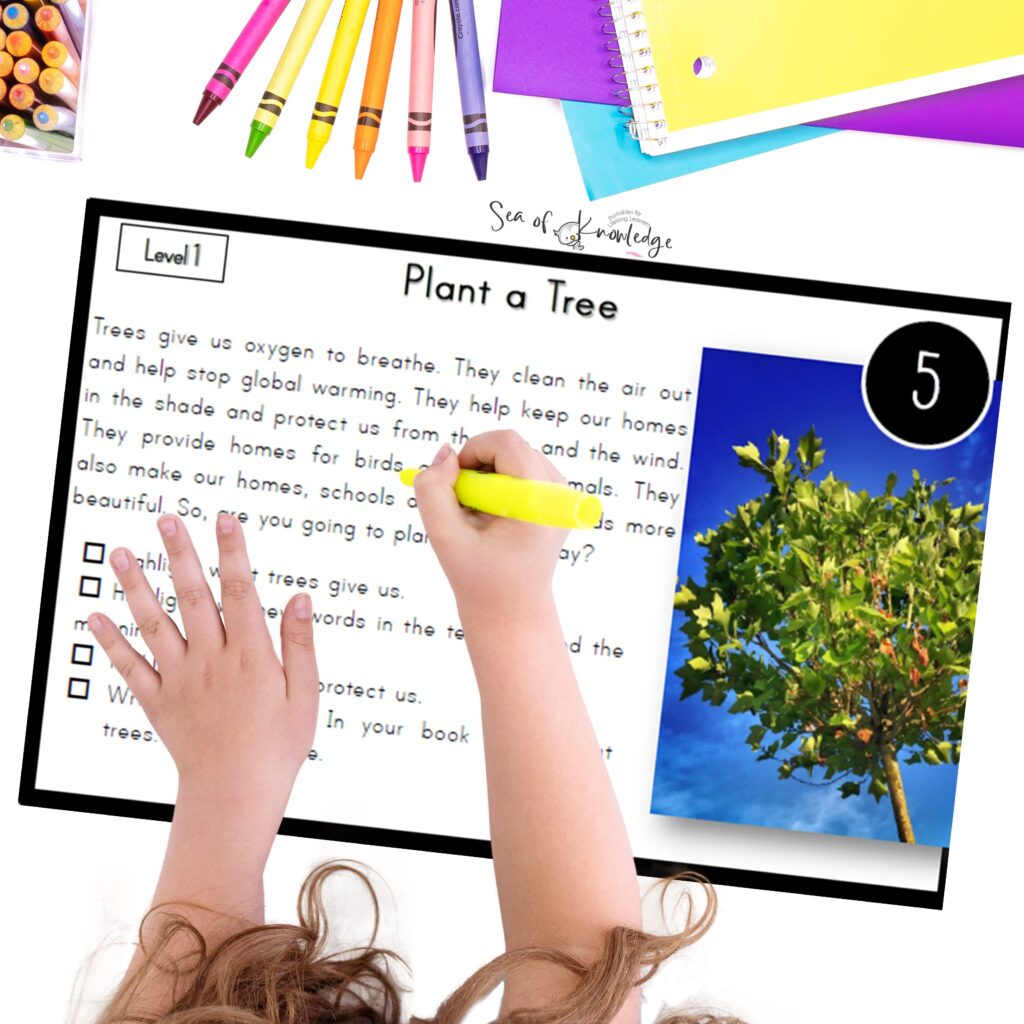 Student using Earth Day reading comprehension task cards at a small group table with laminated cards and writing tools.