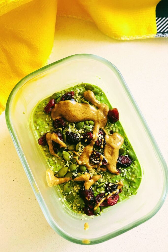 A bowl of creamy matcha oats with almond milk, topped with dried cranberries and a dusting of matcha powder.