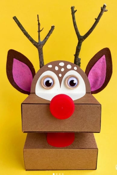 Brown cardboard reindeer puppet with a red pom-pom nose and an open mouth