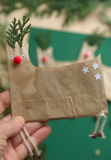 Reindeer decorated paper bag holding a Christmas card