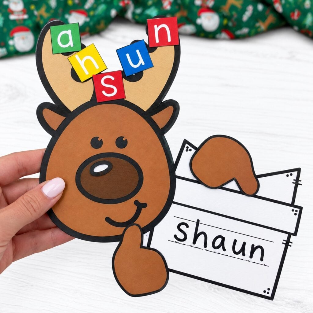 Paper reindeer name craft with colorful letter tiles on its antlers and Shaun on a writing strip