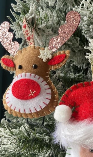 Stitched felt reindeer face ornament hanging on a Christmas tree