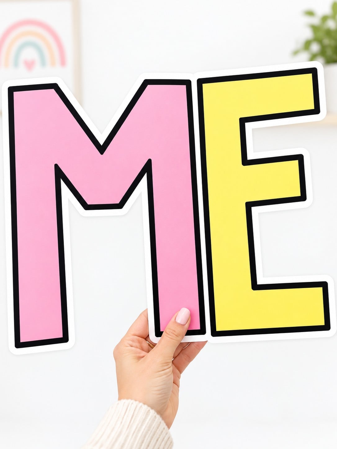 Hand holding large pink M and yellow E printable bulletin board letters.